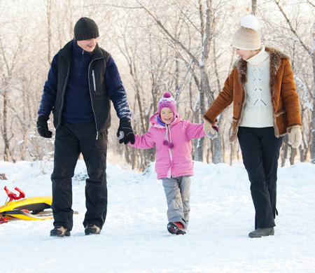 Mother and Father walking with young girl on a snowy winter day